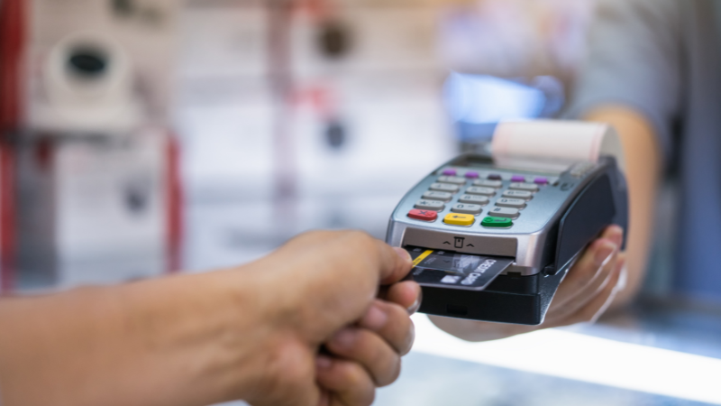 A person making a payment by inserting a business credit card into a card terminal, representing a common use for business credit.